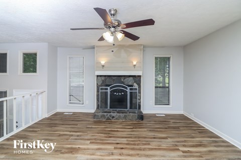 A living room with a fireplace and a ceiling fan.