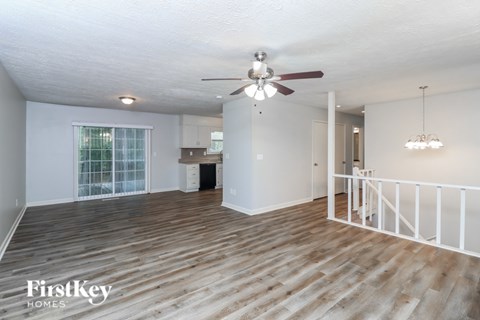 A spacious room with wooden flooring and a ceiling fan.