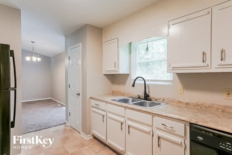 A kitchen with white cabinets and a black refrigerator.