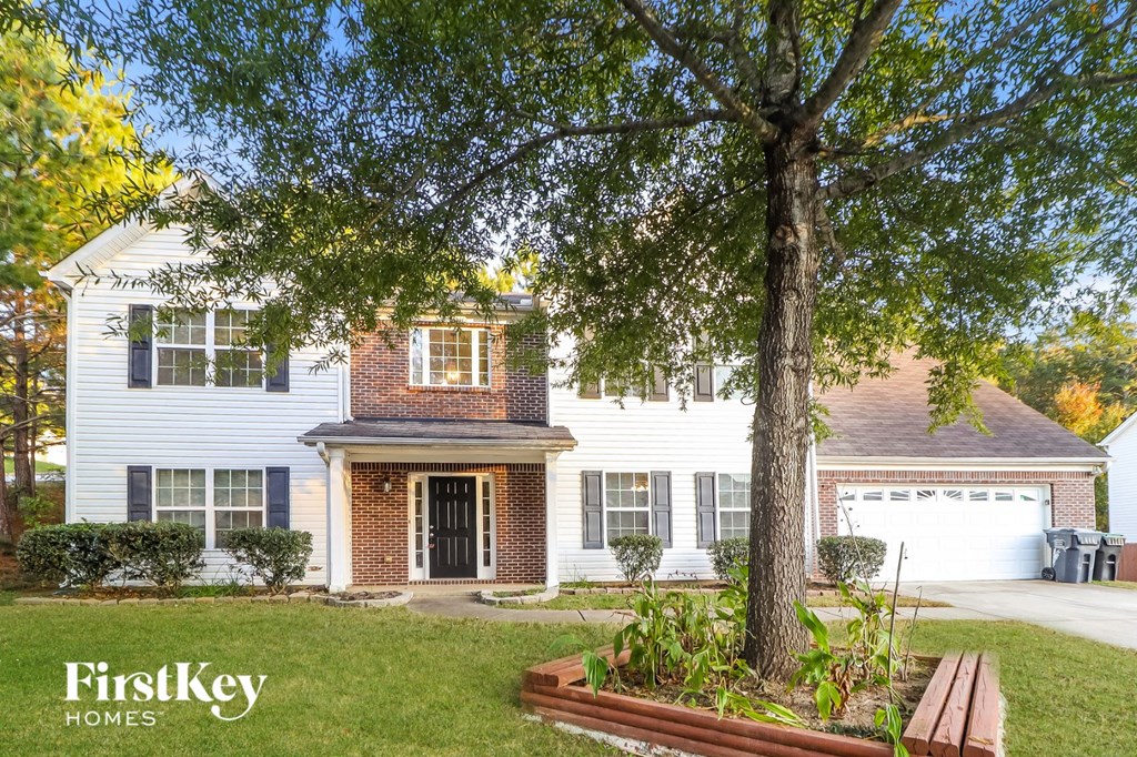a white house with a large tree in a front yard