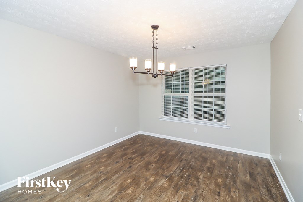 an empty living room with a window and a chandelier