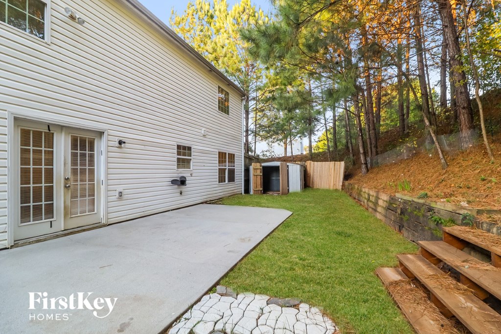 a side view of a white house with a concrete driveway and a yard with trees