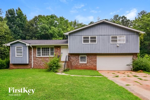 a blue house with a lawn and a driveway