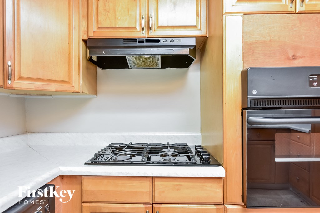 a kitchen with wooden cabinets and a stove top oven and a microwave