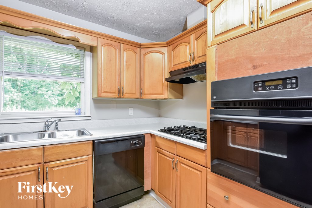 a kitchen with wood cabinets and black appliances and a window