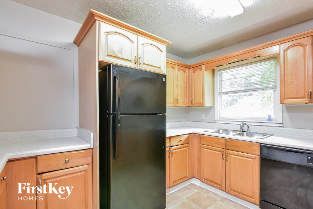 a kitchen with wooden cabinets and a black refrigerator