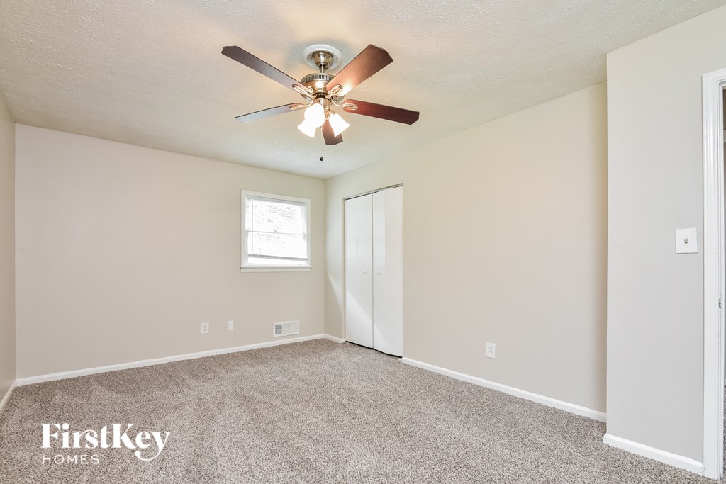the spacious living room with ceiling fan and carpet