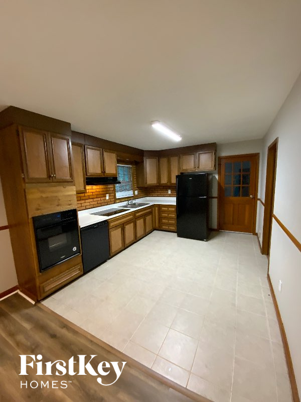 A kitchen with wooden cabinets and a black fridge.