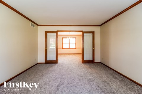 A room with a carpeted floor and a window with sunlight shining through.