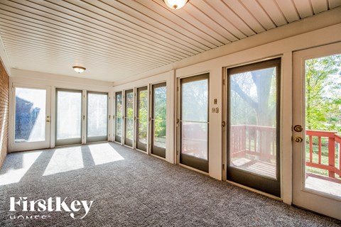 A sunny day in a house with a balcony and a view of the trees.