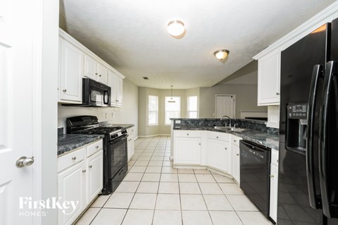 A kitchen with black appliances and white cabinets.