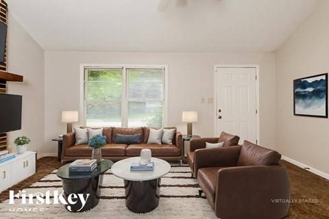 A living room with a brown leather couch and a glass coffee table.