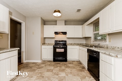 A kitchen with a black oven and white cabinets.