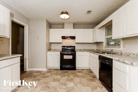 A kitchen with a black oven and white cabinets.