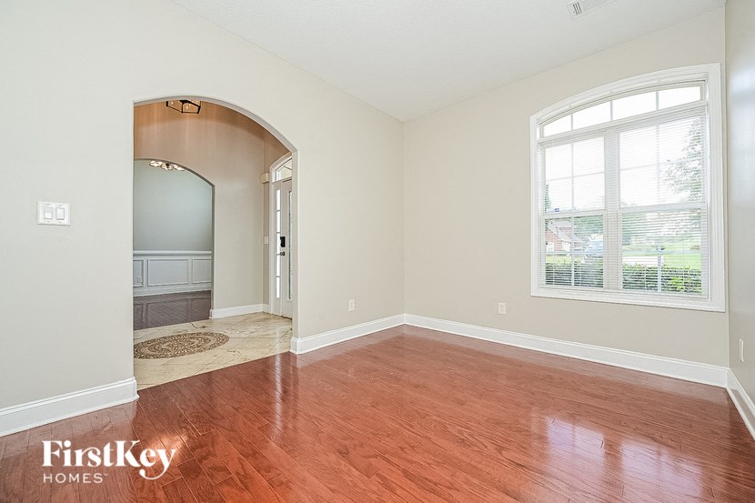an empty living room with wood floors and a large window
