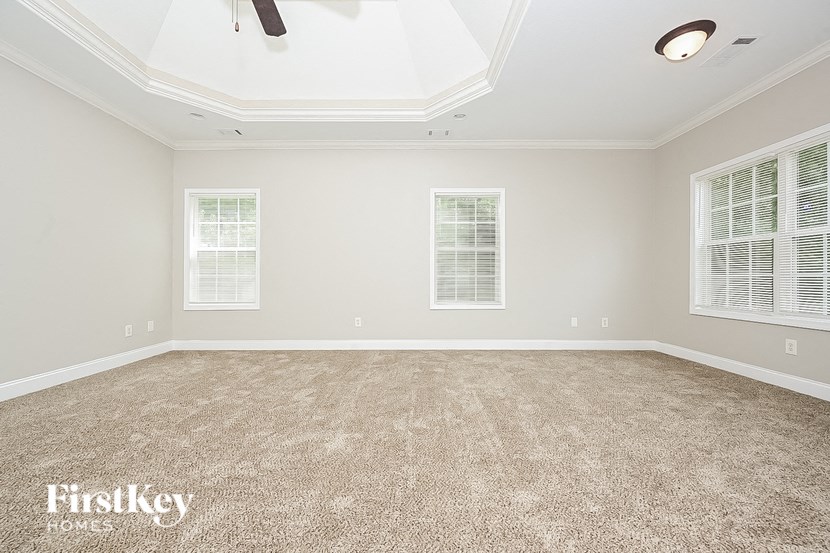 a empty living room with a carpeted floor and three windows