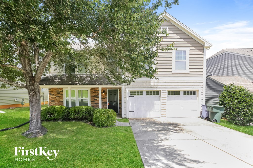 a white house with a white garage door and a tree