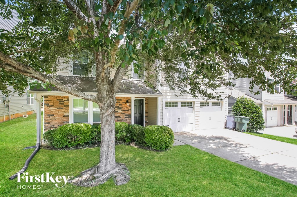 a large tree in front of a white house