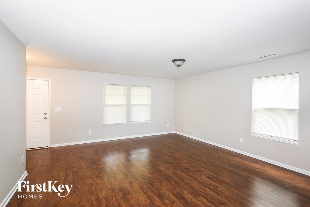 the living room of a house with wood floors and white walls