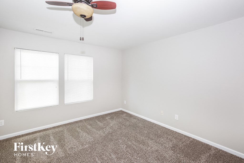 a empty room with a ceiling fan and two windows