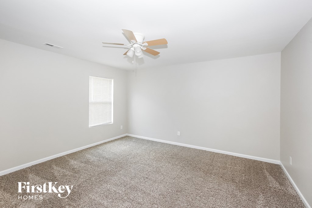 a bedroom with white walls and a ceiling fan