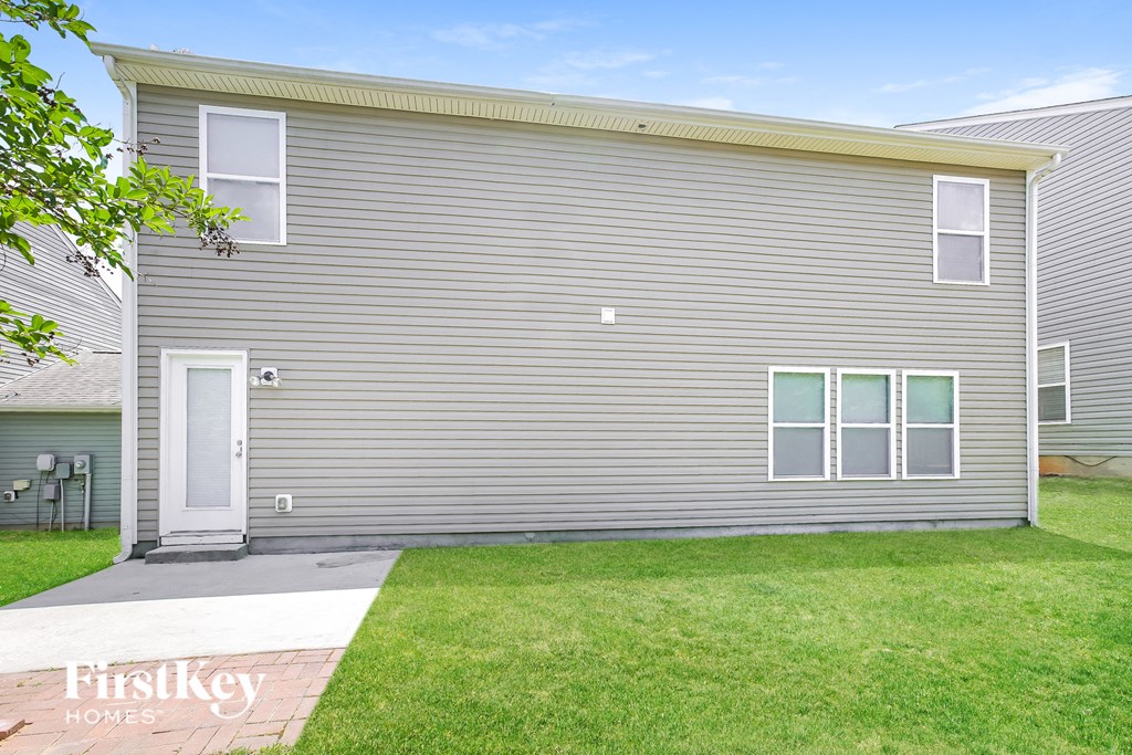 a side view of a gray house with a yard and a sidewalk