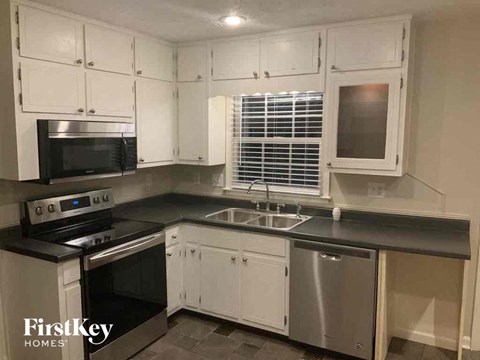 a kitchen with white cabinets and a black counter top