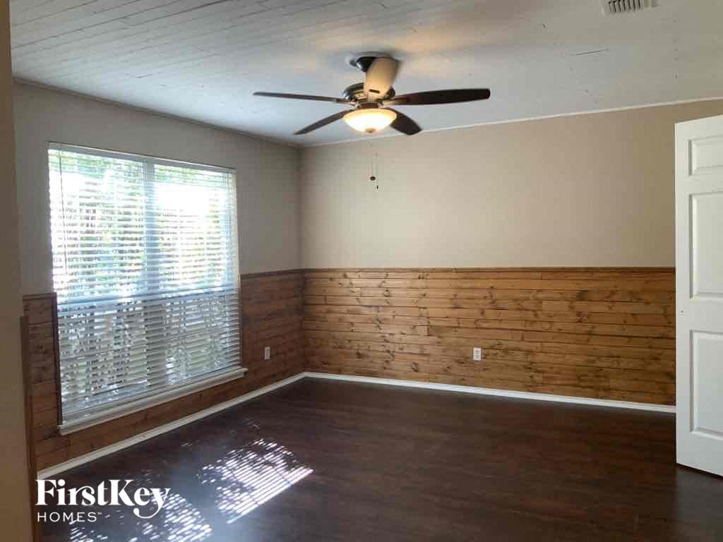 an empty room with a wooden accent wall and a ceiling fan