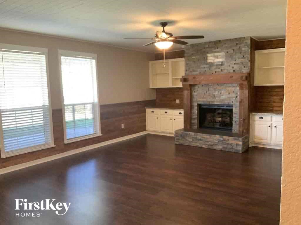 an empty living room with a fireplace and a ceiling fan