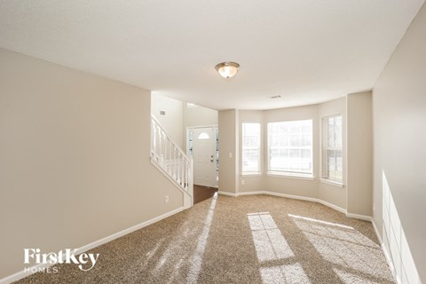 A spacious room with a carpeted floor and a staircase leading to another room.