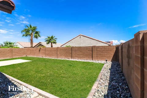 a backyard with a fence and grass and palm trees