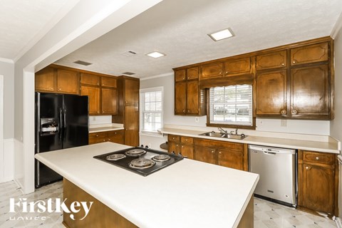 A kitchen with wooden cabinets and a black fridge.