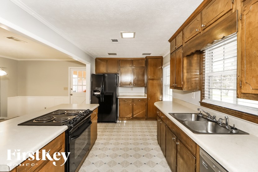 A kitchen with wooden cabinets and a black refrigerator.