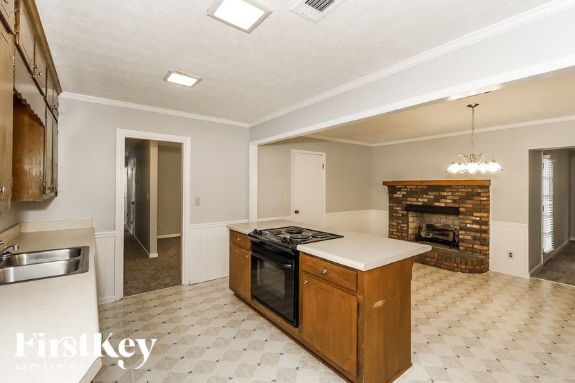 A kitchen with a wooden island and a fireplace in the background.