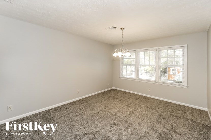 A room with a carpeted floor and a window with blinds.