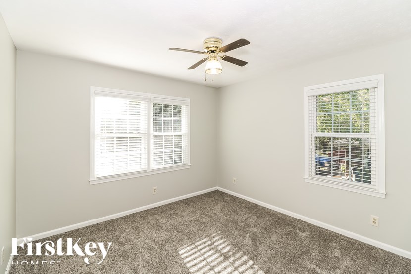 A room with a ceiling fan and two windows.