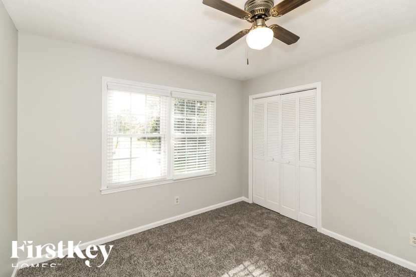 A room with a ceiling fan and a window with blinds.
