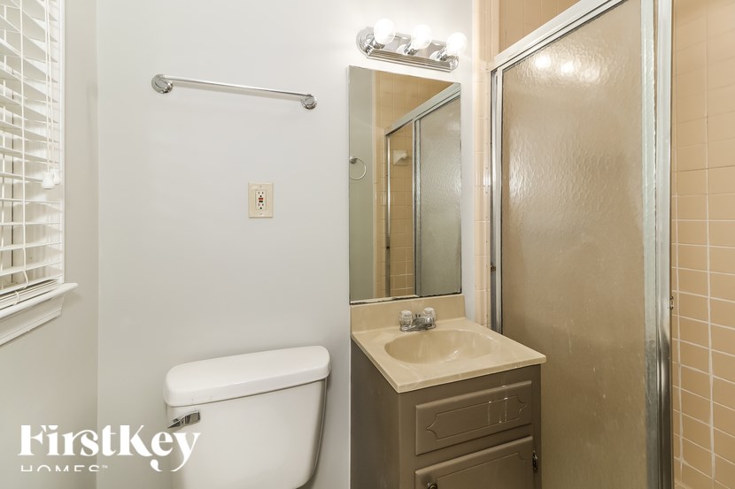 A bathroom with a toilet, sink, and mirror.
