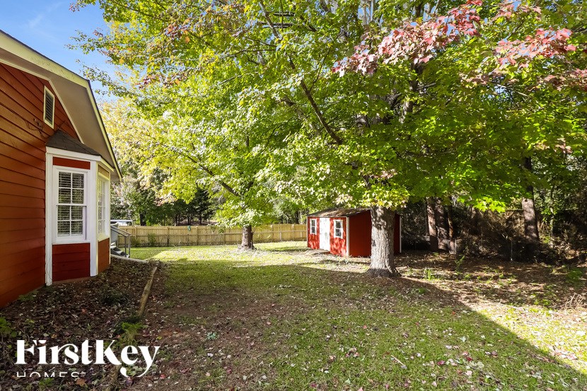 A backyard with a tree, a shed, and a small house.