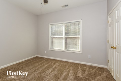 a bedroom with a large window and a carpeted floor