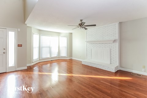 an empty living room with a fireplace and a ceiling fan