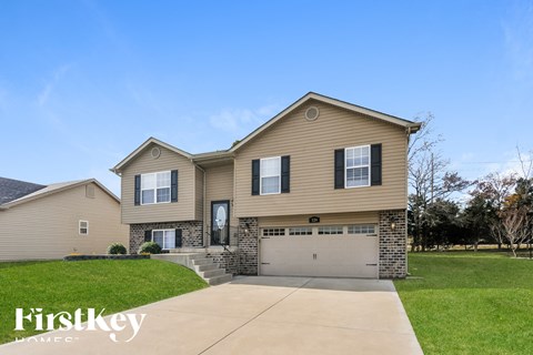 a beige house with a garage door and a lawn