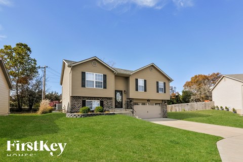 a beige house with a driveway and a lawn