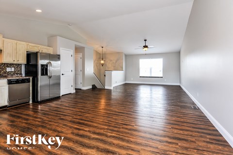 an empty kitchen and living room with wood flooring and stainless steel appliances