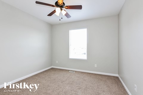 a bedroom with a ceiling fan and a carpet