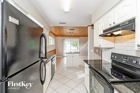 A kitchen with a black fridge and a black stove top oven.