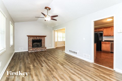 A spacious living room with a fireplace and a ceiling fan.