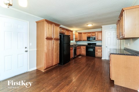 A kitchen with wooden cabinets and a black fridge.