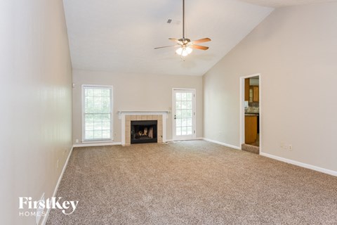 an empty living room with a fireplace and a ceiling fan