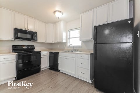 a white kitchen with black appliances and white cabinets